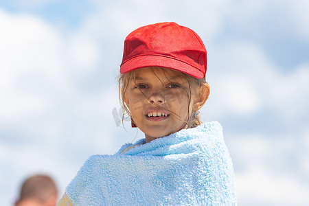 一个戴着红色帽子的女孩的画像，用毛巾裹着天空