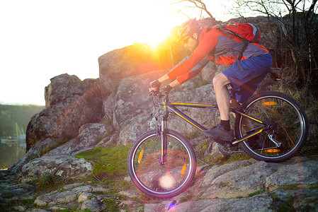 日落时分，骑山地自行车的骑自行车者在春天步道上落基山下。