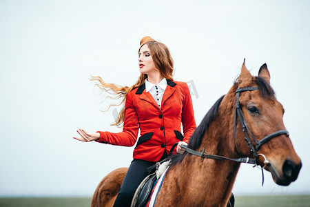 红色羊毛衫和黑色高筒靴的红发骑师女孩