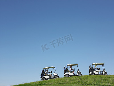 高尔夫球手在湛蓝的天空下连续驾驶手推车