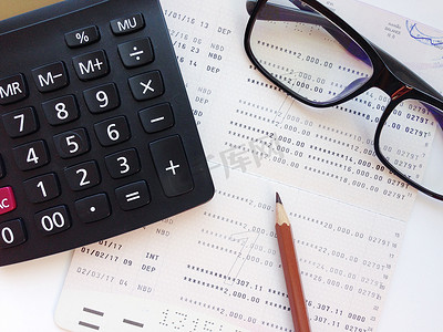 白色背景中的铅笔、计算器、眼镜和储蓄账户存折或财务报表