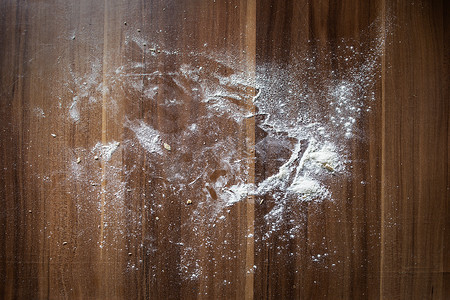 面粉散落在棕色的木桌背景上。