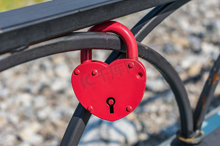 心形挂坠摄影照片_挂在篱笆上的红色心形吊坠锁作为婚姻的象征