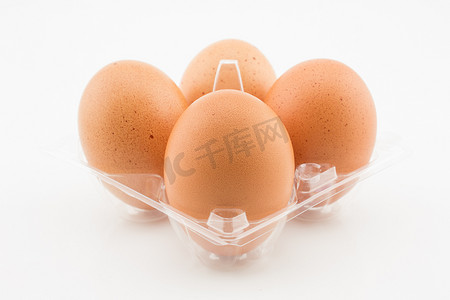白色背景中突显的塑料托盘中的四个鸡蛋