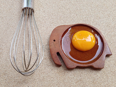 兰象形字摄影照片_木象形碟上的蛋黄，胶合板上有打蛋器