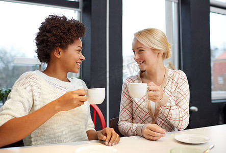 快乐的年轻女性在咖啡馆喝茶或喝咖啡