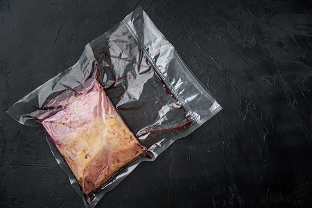 用塑料包装切割的顶级沙朗牛肉，黑色背景，顶部视图，带有文本复制空间
