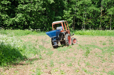播种机器摄影照片_农民用拖拉机在田间播种荞麦种子