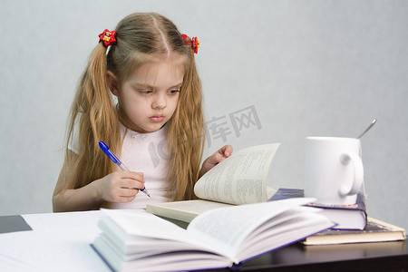 女孩翻阅书籍并在一张纸上写下摘要坐姿