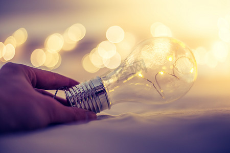 想法和创新：带 LED 的灯泡躺在床上，双手接触。