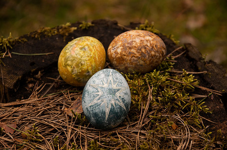 复活节在苔藓上涂上棕色、黄色、蓝色的鸡蛋，上面有星星
