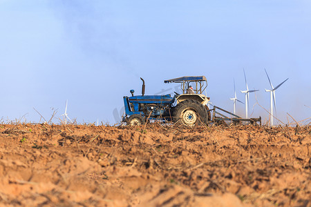 拖拉机农民用风力涡轮发电机准备农田