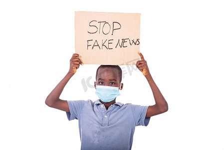 小男孩拿着一张纸，上面写着 STOP FAKE NEWS