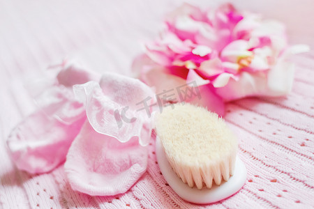 初生女婴的第一件配饰——粉色短靴、带绢花的帽子和小毛刷。