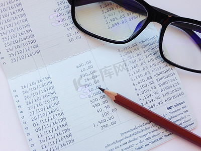 财务报表摄影照片_白色背景中的铅笔、眼镜和储蓄账户存折或财务报表