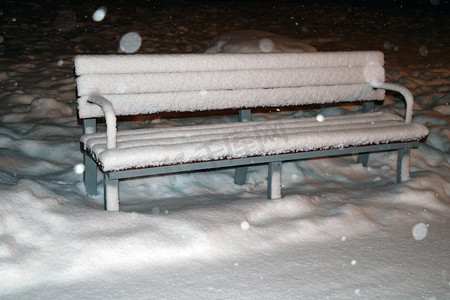 晚上箱子摄影照片_傍晚公园白雪覆盖的长椅。