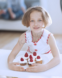 厨房场景摄影照片_拿着纸杯蛋糕盘子的年轻女孩
