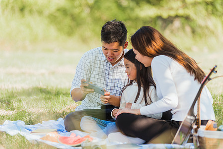 幸福的家庭坐在野餐毯上享受户外乐趣自拍