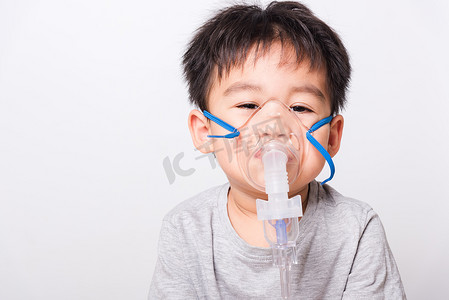 人脸真面摄影照片_特写亚洲人脸，小男孩生病，他用蒸汽吸入