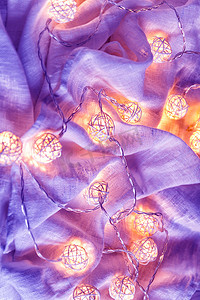 织物褶皱上带球灯的花环背景 i
