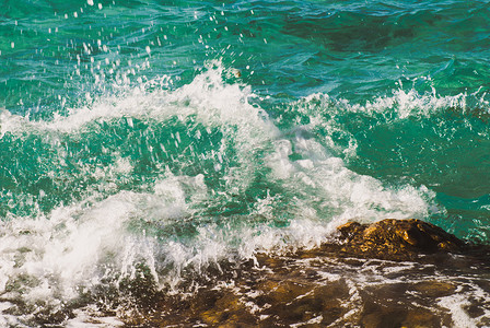 有波纹摄影照片_美丽清澈的绿松石海水表面照片，海景背景上有波纹和明亮的飞溅，水平图片
