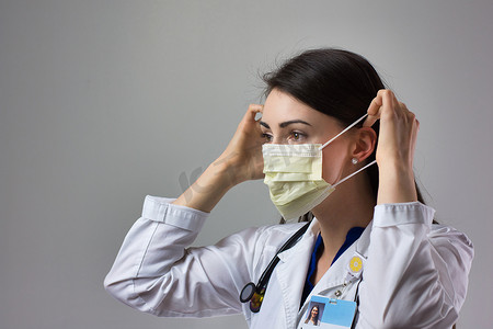 开业摄影照片_女性医疗保健专业人员展示正确戴上口罩以防止冠状病毒感染。