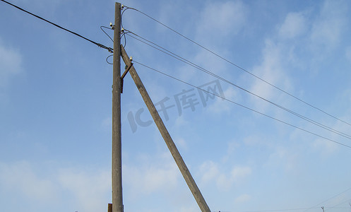 蓝天背景上带电线和绝缘体的木制旧 0.4 kV 电源线支架