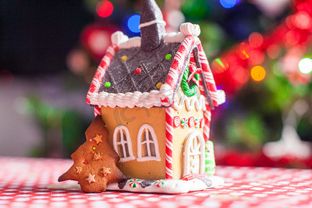 甜糖果装饰的姜饼屋在明亮的圣诞树背景与诗歌选