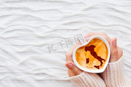 剪影咖啡杯摄影照片_女人拿着一杯带有意大利肉桂剪影的热咖啡。