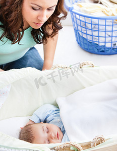 细心的妈妈留意着睡在婴儿床里的婴儿