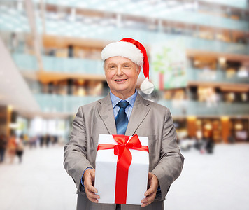 西装摄影照片_穿着西装的微笑男士和带礼物的圣诞老人助手帽