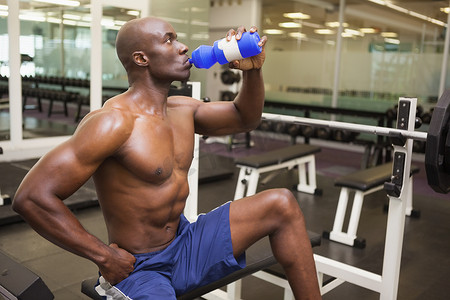 在健身房喝能量饮料的肌肉男