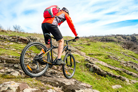 骑山地自行车的红色夹克的骑自行车者在落基山下。