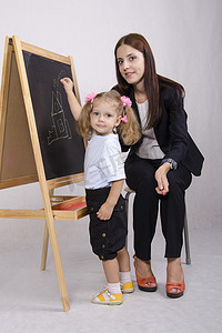小女孩在 Board house 上画画，教育家帮助她