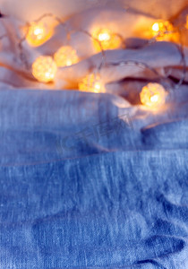 织物褶皱摄影照片_蓝色织物褶皱上带灯的花环背景