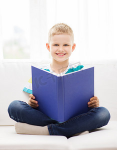微笑的小男孩在沙发上看书