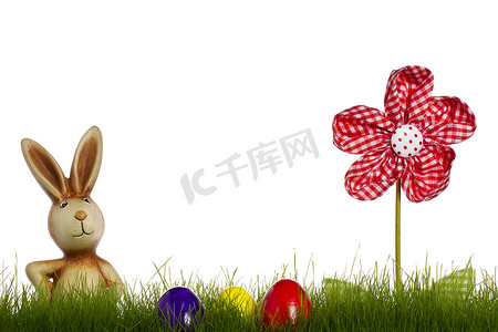 兔子黄色摄影照片_在草后的复活节兔子与帷幔花和复活节彩蛋