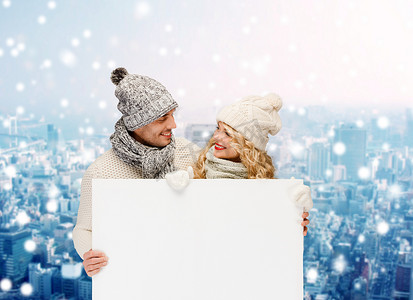 情侣海报摄影照片_穿着冬装、拿着白板微笑的情侣