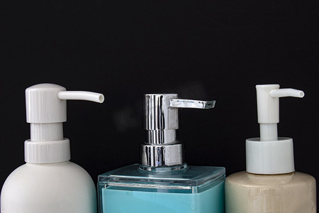 保湿器摄影照片_黑色背景下用于浴室或厨房水槽的彩色皂液器的特写顶视图