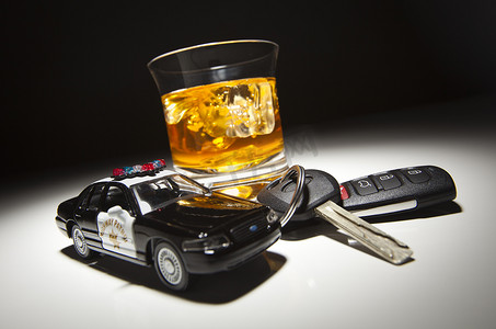 饮酒驾驶摄影照片_在酒精饮料和钥匙旁边的高速公路巡逻警车