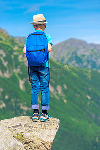 攀岩男孩摄影照片_山上背着背包的男孩站在岩石上，看起来