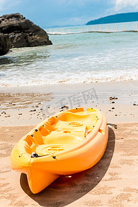 大海背景上的黄色皮划艇躺在沙滩上