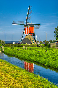 农业风车摄影照片_小孩堤防、荷兰或荷兰的风车和水运河。