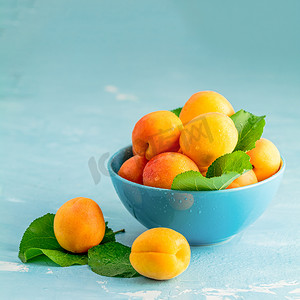 甜橙摄影照片_蓝色混凝土苏上蓝色碗中的新鲜甜橙杏