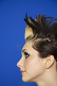 彩色背景下留着尖刺头发的年轻女性的侧视图