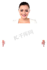 拿着空白的白色广告板的微笑的妇女