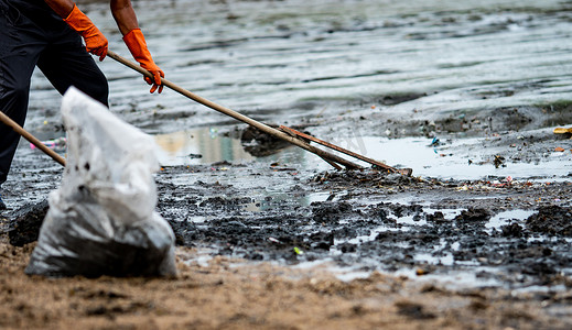 志愿者用耙子将海里的垃圾扫出海面。 