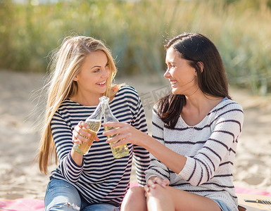 快乐的年轻女性在沙滩上喝啤酒