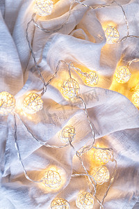织物褶皱上带球灯的花环背景