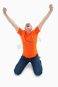 穿着橙色 T 恤的成熟男人跪着欢呼